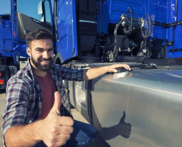 Truck driver opening reservoir tank to refuel the truck and holding thumbs up.